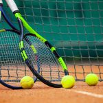 Two tennis rackets and balls leaned against the net.